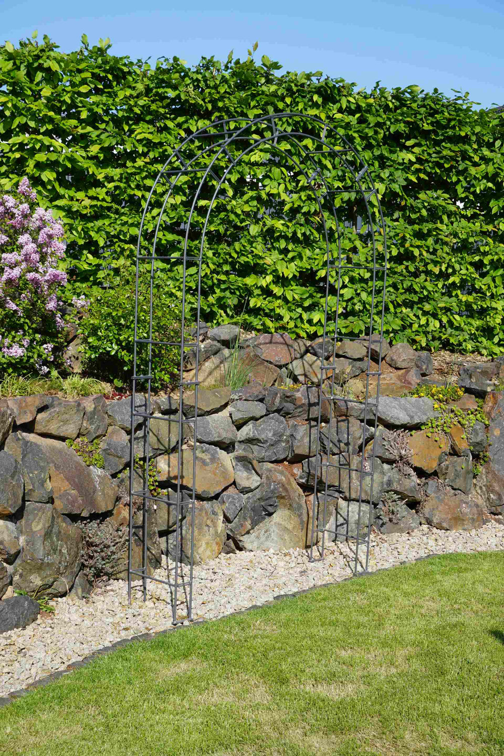 Rosenbogen Cremona vor einer Steinmauer | Pulverbeschichtet anthrazit Rosenbogen Cremona vor einer Steinmauer | Pulverbeschichtet anthrazit