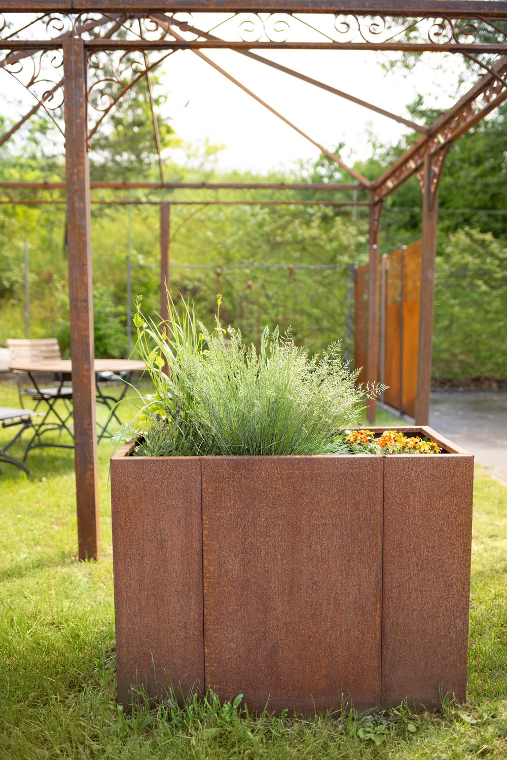 Hochbeet Monterosso freistehend in einem Garten mit ELEO Pavillon im Hintergrund | Cortenstahl Hochbeet Monterosso freistehend in einem Garten mit ELEO Pavillon im Hintergrund | Cortenstahl