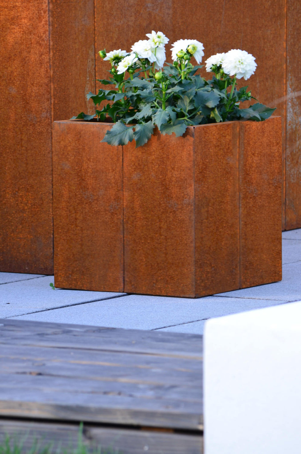 Pflanzkübel Vernazza 40x40x40 cm aus Cortenstahl bepflanzt vor einem Hochbeet aus Cortenstahl Pflanzkübel Vernazza 40x40x40 cm aus Cortenstahl bepflanzt vor einem Hochbeet aus Cortenstahl