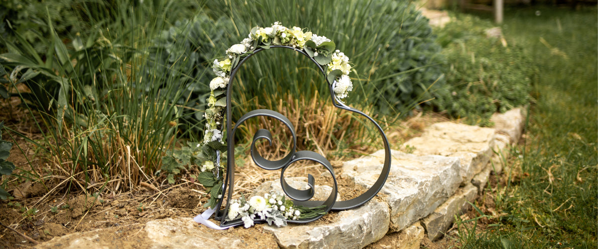 Herzen Vercelli und Biella aus Metall in Anthrazit, dekoriert mit weißen Blumen als Geschenk.